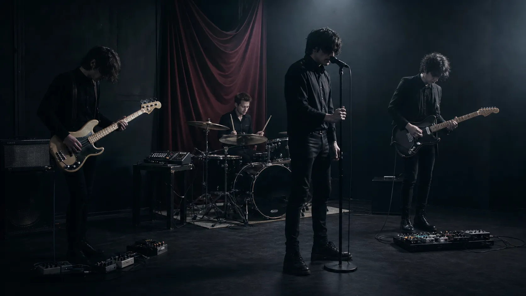 An anonymous gothic rock group rehearses with bass, guitar, drums, a drum machine, and a standing vocalist.